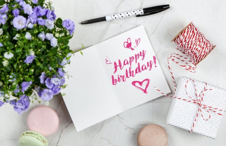 happy birthday card beside flower thread box and macaroons