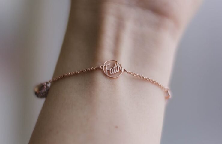 person wearing pink gold colored faith bracelet